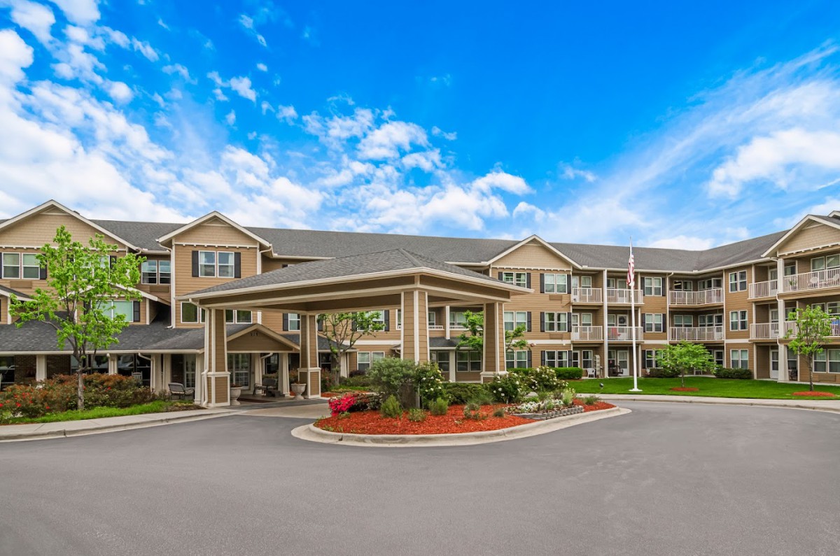 A spacious residential building with landscaped surroundings under a partly cloudy sky.