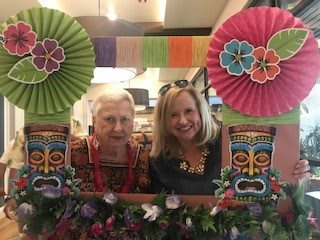Two people smiling at a party with colorful decorations and a festive frame.