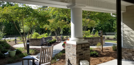 A serene outdoor space featuring a columned porch and beautifully landscaped garden.