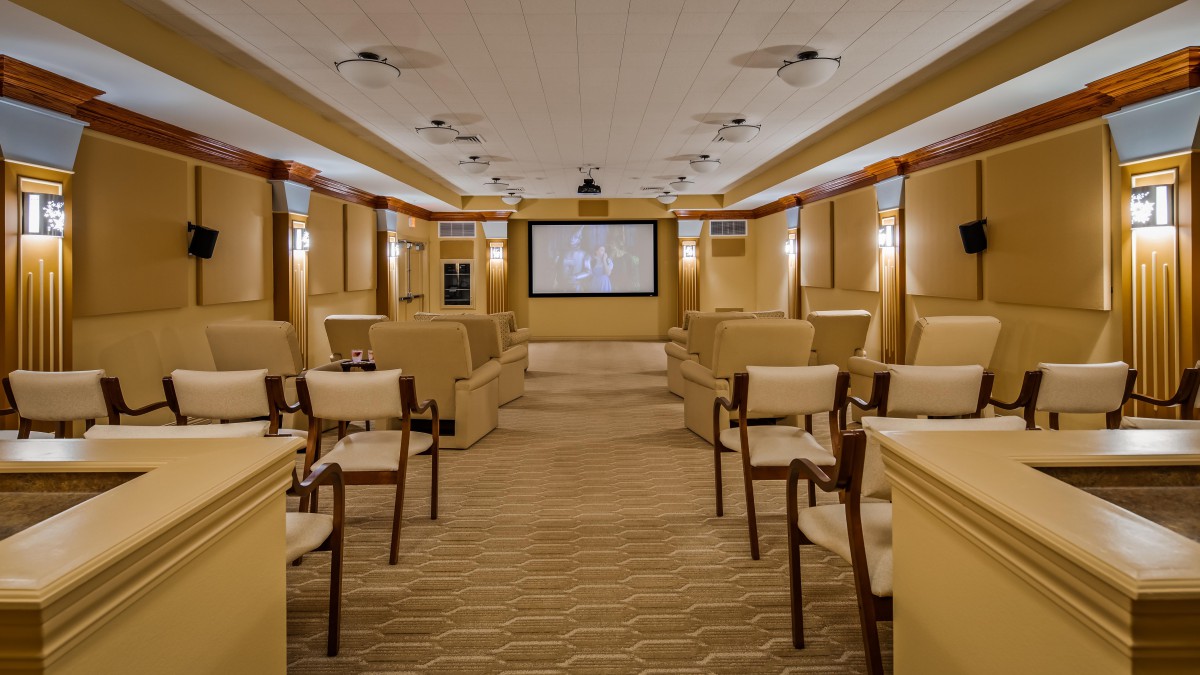 A cozy home theater with rows of comfortable seating and a large projector screen.