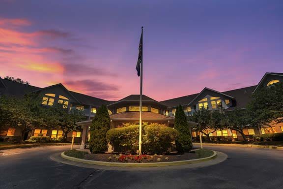 A hotel's grand entrance at sunset with a flagpole in the center.