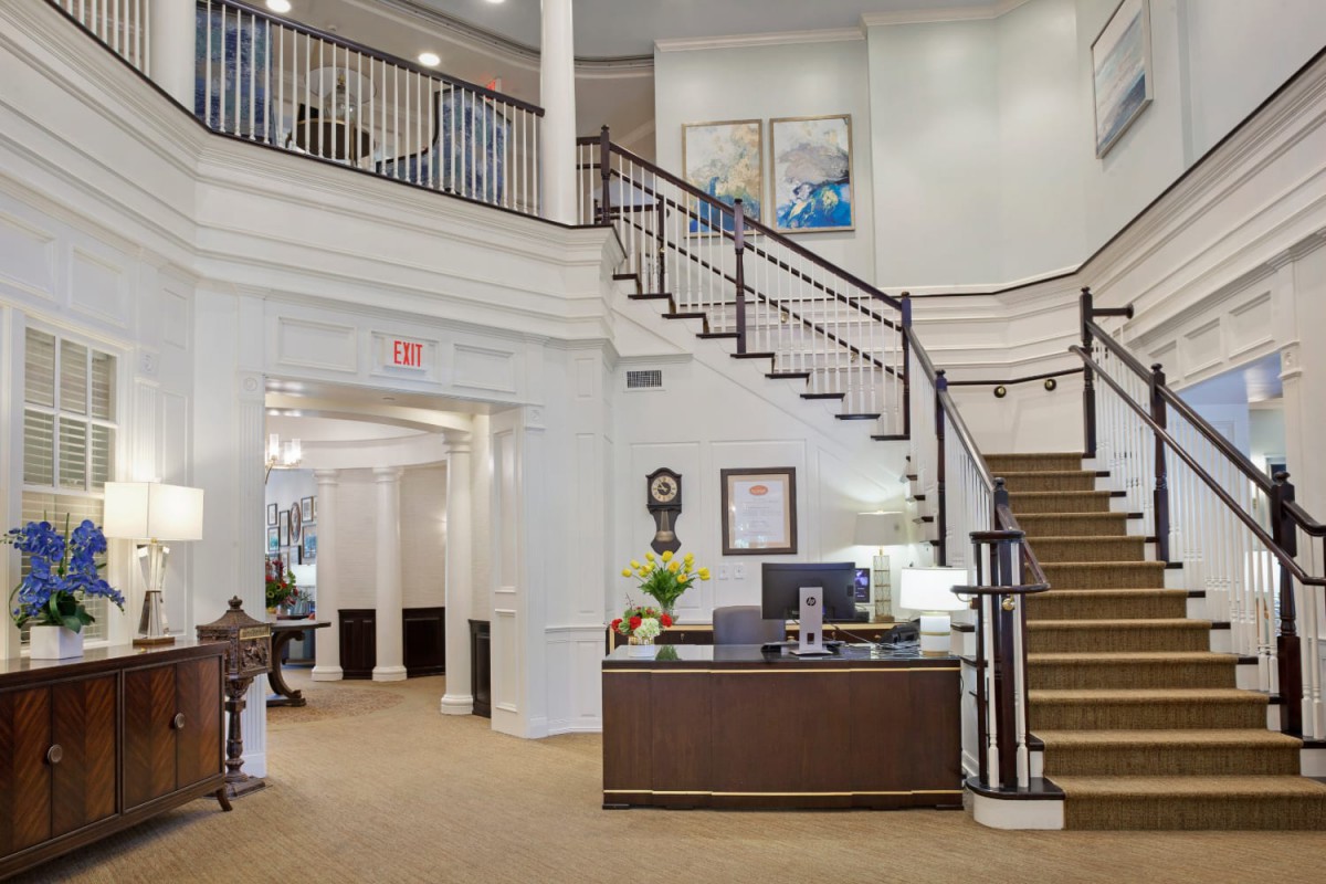 A spacious lobby area featuring a reception desk and a grand staircase.