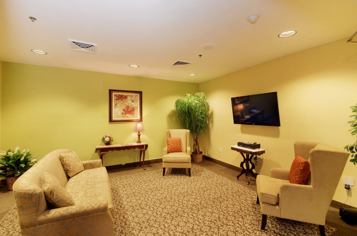 A cozy living room with modern decor, featuring a sofa, chairs, a television, and wall art.