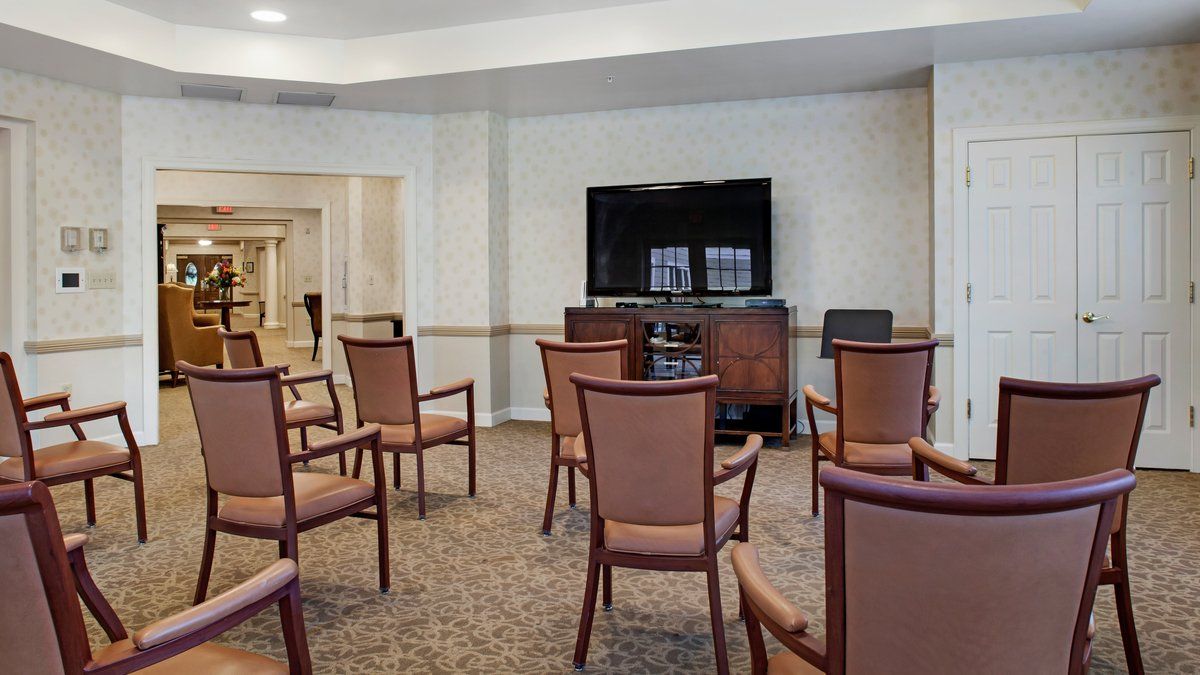 A conference room with a television, several chairs arranged in rows, and a table at the front.