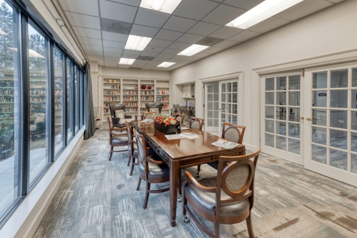 A well-lit conference room with a long wooden table and bookshelves.