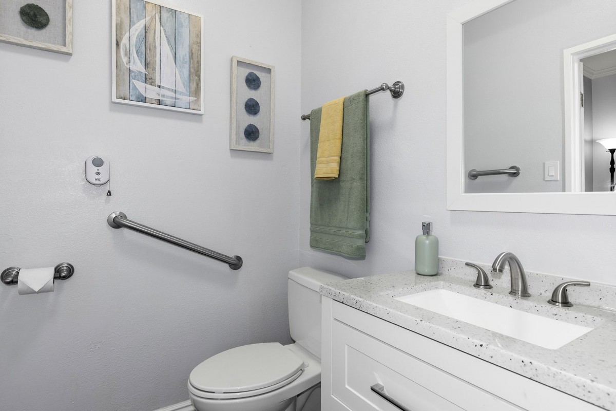 A modern bathroom with a toilet, sink, and colorful towels hanging on the wall.