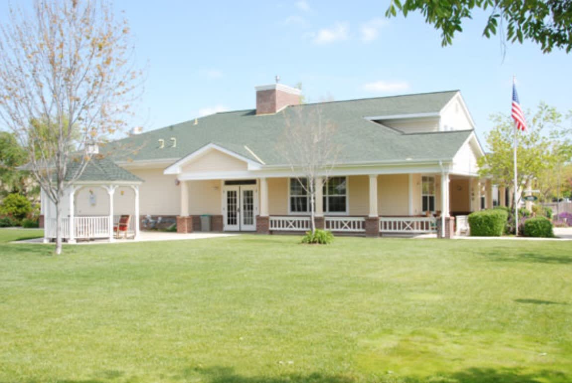 A single-story house with a green roof and spacious lawn.