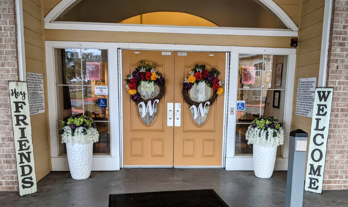 Decorated entrance with floral wreaths and potted plants.