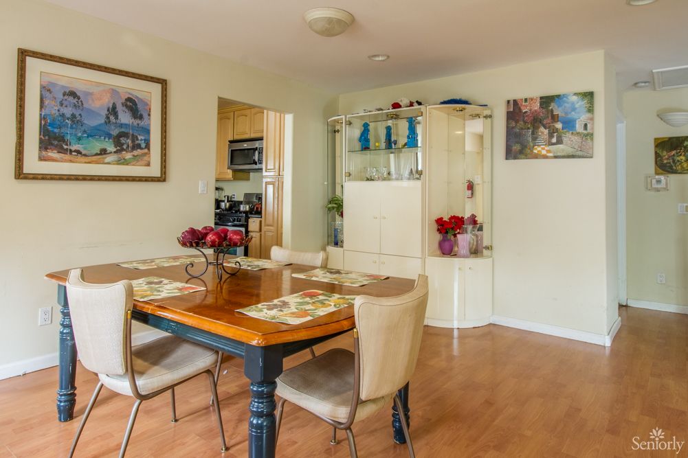 A cozy dining room featuring a wooden table set for four, surrounded by art and decorative elements.
