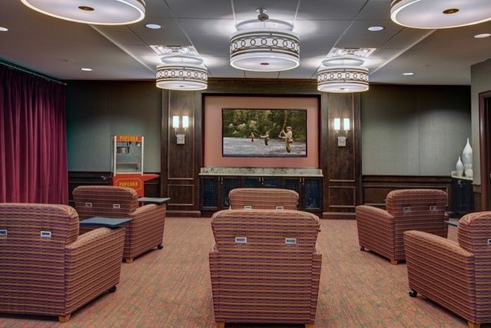 A cozy home theater with plush seating, ambient lighting, and a large screen, featuring a popcorn machine for snacks.