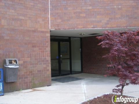An exterior view of a building entrance with a glass door, surrounded by brick walls and landscaping.