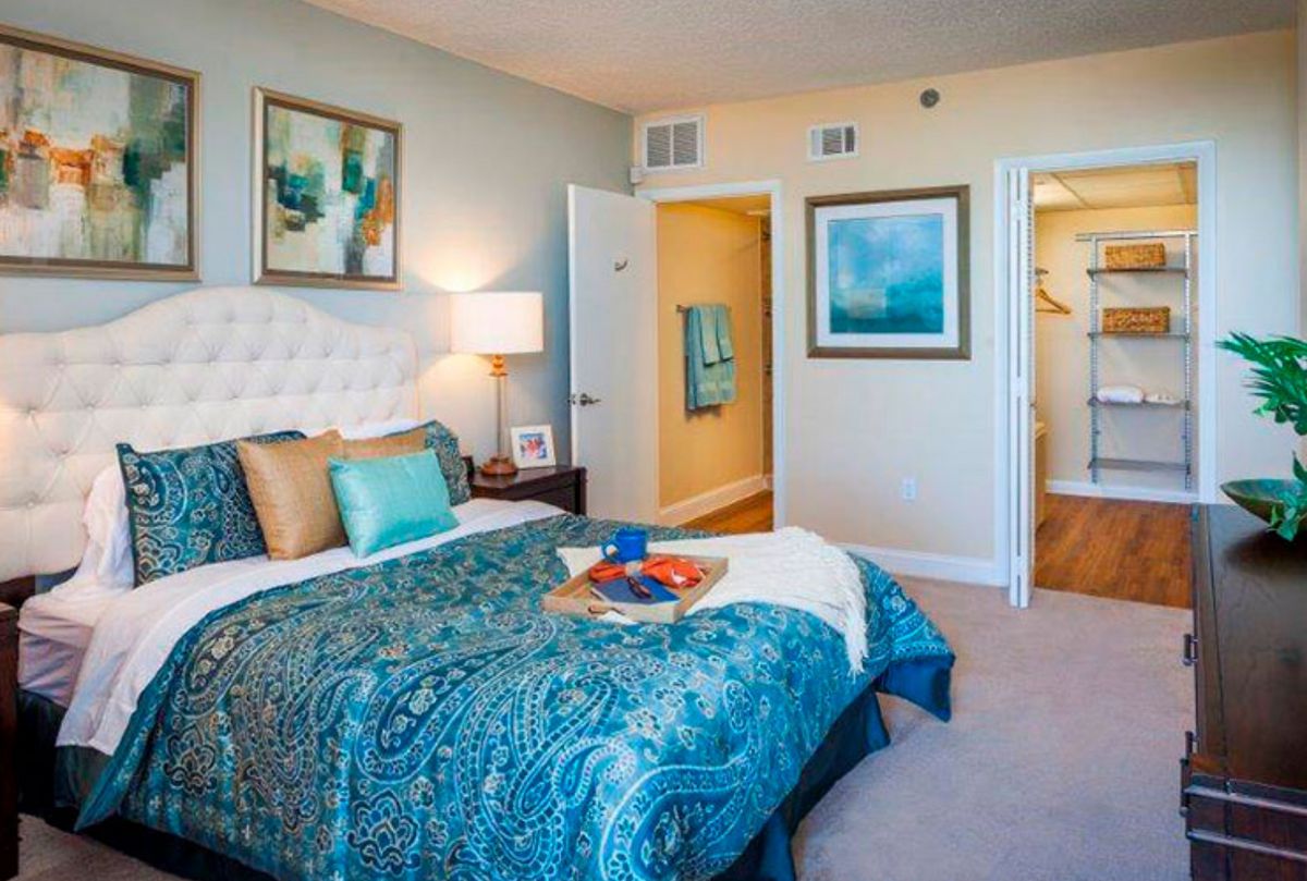 A cozy bedroom with stylish decor, including a bed with blue bedding and artwork on the walls.
