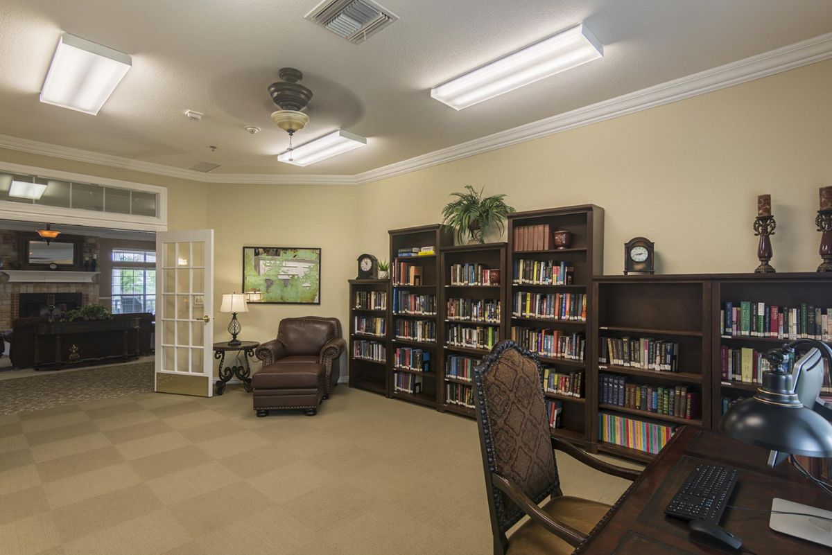 A cozy library room with bookshelves, an armchair, and a desk for reading.