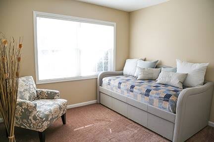 A cozy bedroom with a daybed and a large window letting in natural light.