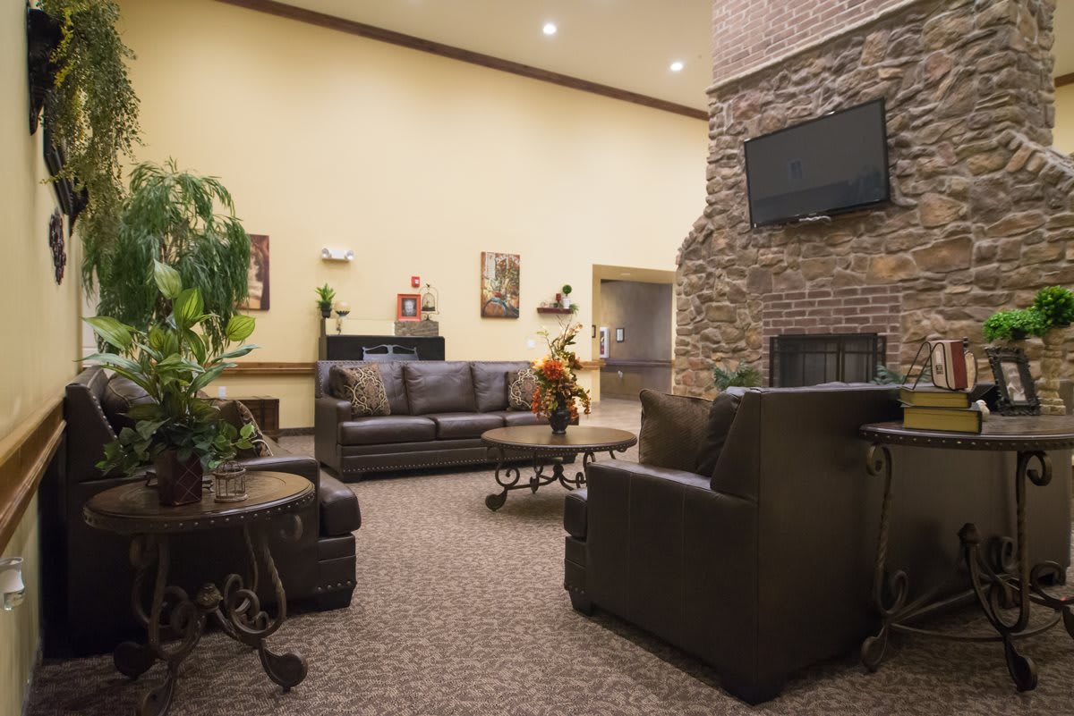 A cozy lobby area with leather sofas, armchairs, a fireplace, and a mounted television.