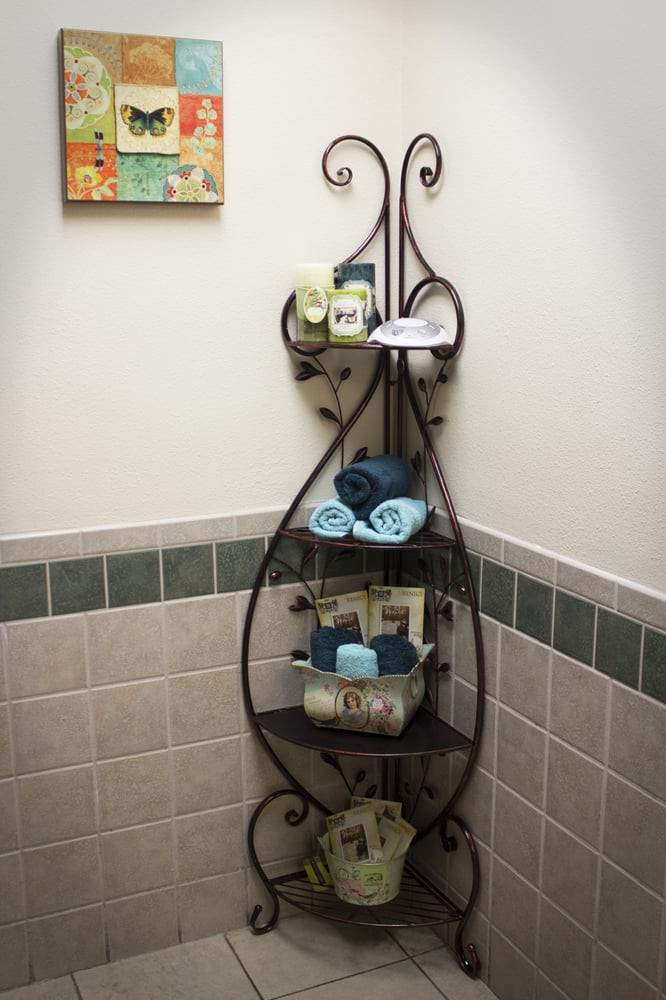 A decorative iron rack holding neatly arranged towels and toiletries in a bathroom corner.