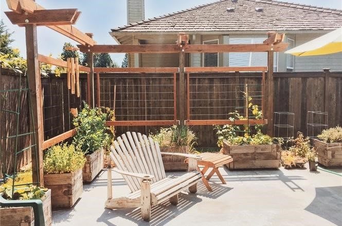 A cozy backyard patio with a wooden chair and planters, perfect for relaxation.