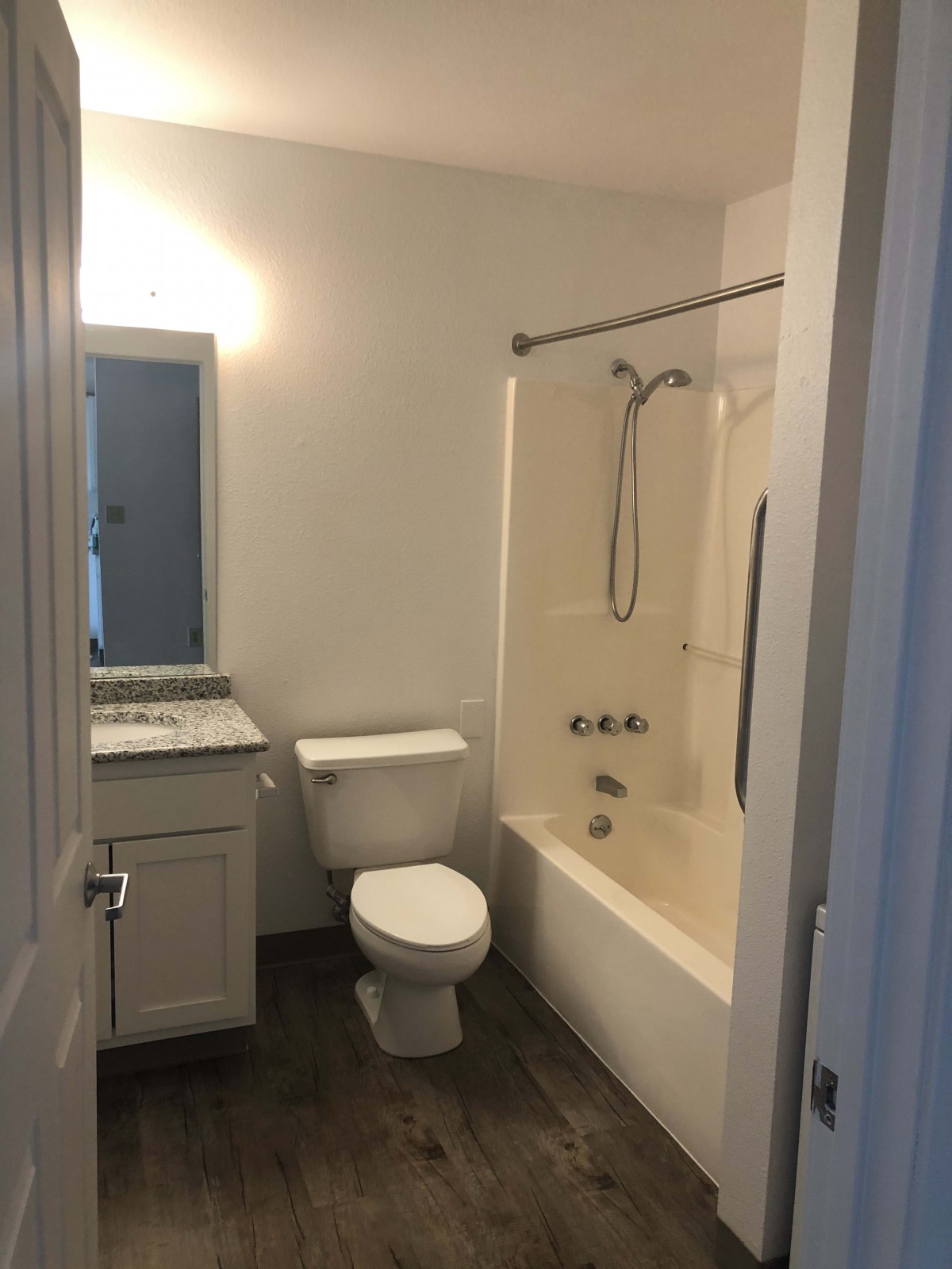 A small bathroom featuring a toilet, bathtub with shower, sink, and mirror.