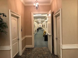 A long hotel hallway with multiple doors and warm lighting.