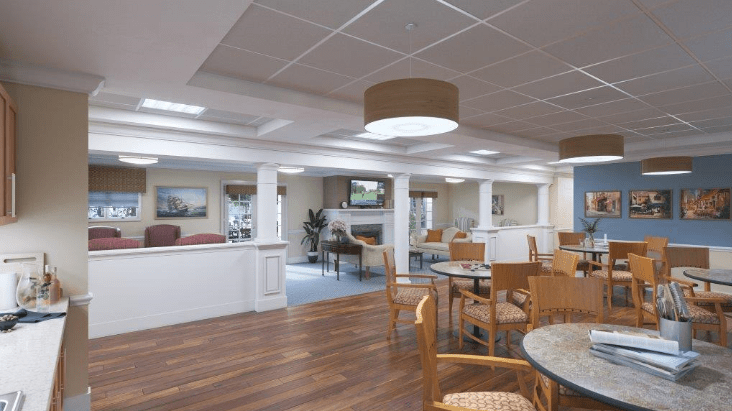 A spacious and well-lit room with wooden floors, tables, and seating areas.