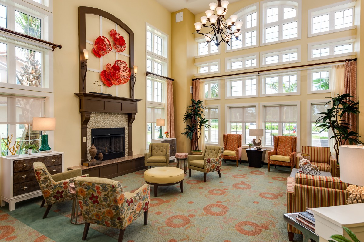 A spacious and elegantly decorated lobby with a fireplace, featuring ample seating and large windows allowing natural light.