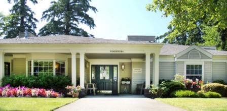 A welcoming entrance with columns and greenery surrounding a residential building.