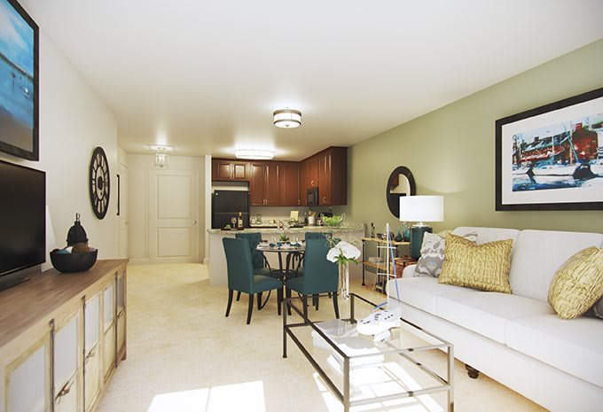 A modern open-concept apartment featuring a cozy living room and dining area, with a kitchen in the background.