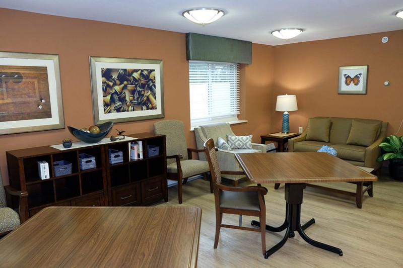 A cozy living room with comfortable seating, artwork on the wall, and a lamp providing soft lighting.