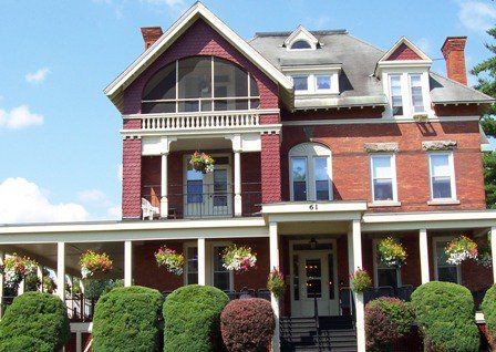 A historic Victorian-style brick house with a large porch and well-maintained garden.