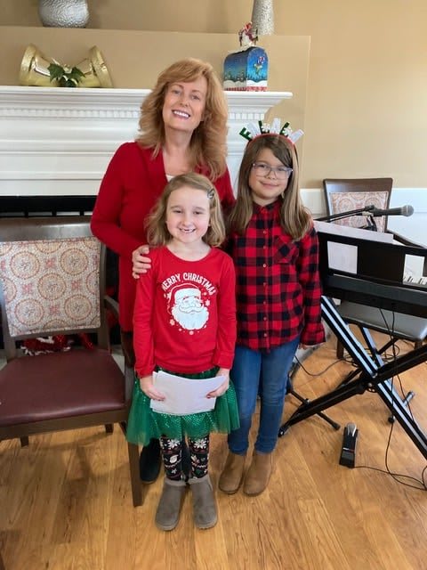 A family posing indoors during the holiday season, with festive outfits and a piano in the background.