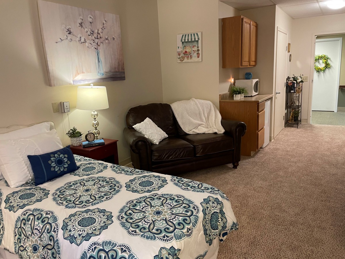A cozy bedroom with a beautifully patterned bedspread, a comfortable sofa, and elegant wall art.