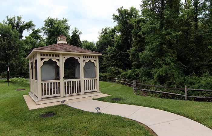 A charming gazebo situated along a curved pathway in a lush garden setting.