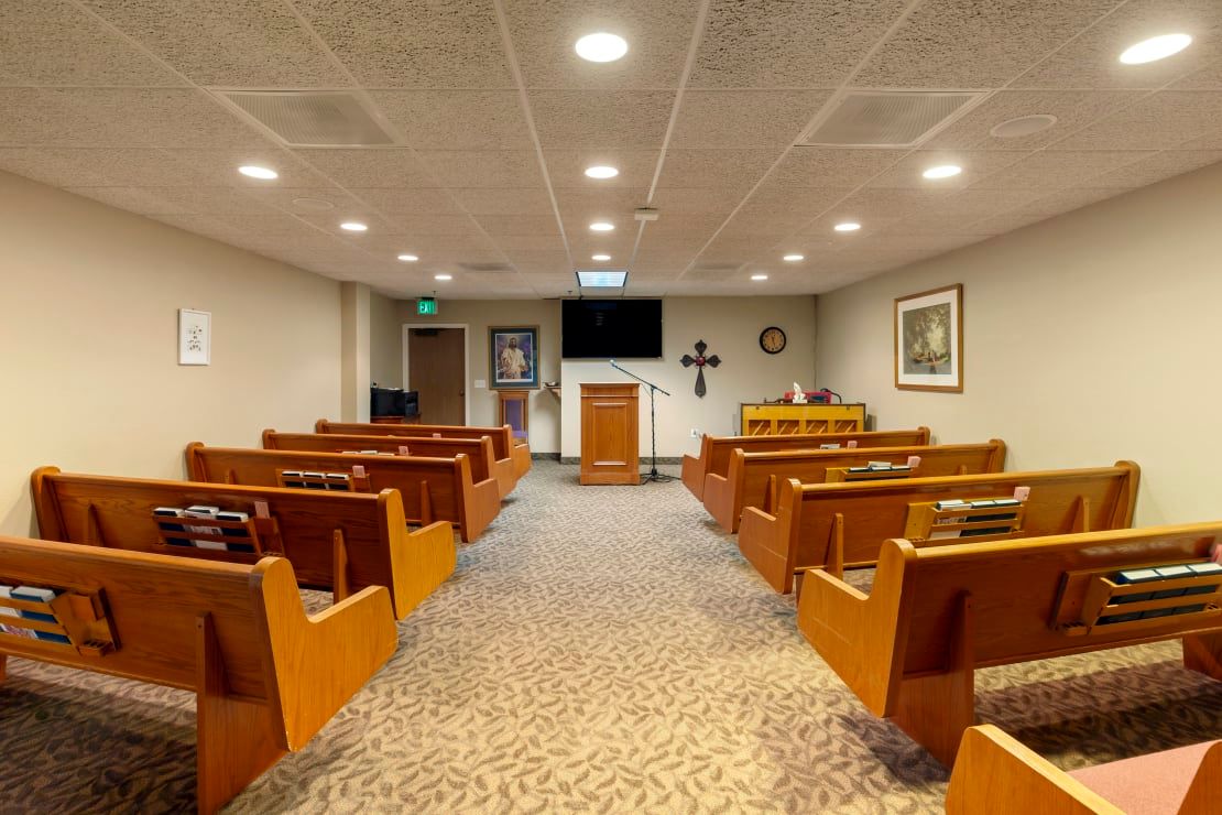 An interior view of a chapel with wooden benches and an altar at the front.
