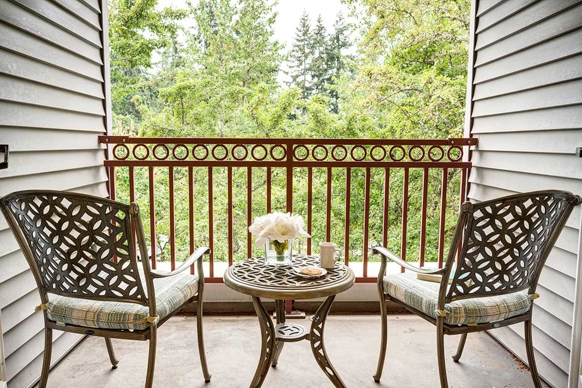 A cozy balcony with a scenic view, featuring two chairs and a table set for relaxation.
