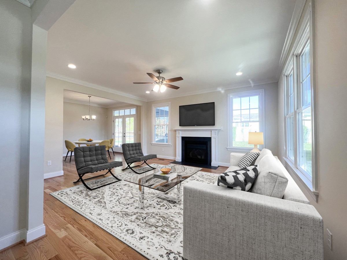 A modern living room with stylish furniture, featuring a sofa, two chairs, a coffee table, and a fireplace under a wall-mounted TV.