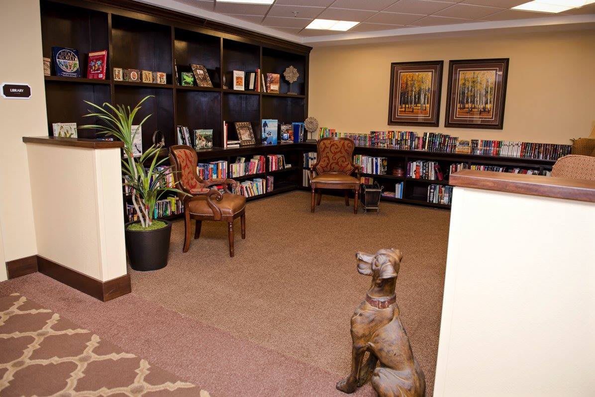 A cozy library corner with bookshelves, comfortable chairs, and a decorative sculpture.
