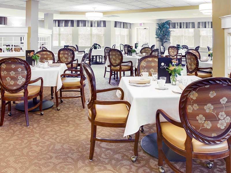 An elegant dining room with neatly arranged tables and chairs, set for a meal.