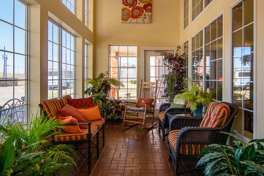 A cozy sunroom filled with natural light, featuring comfortable seating and lush indoor plants.
