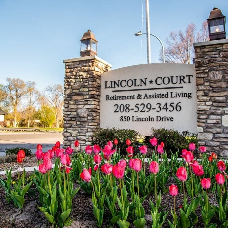 Entrance sign for Lincoln Court Retirement and Assisted Living surrounded by vibrant pink tulips.