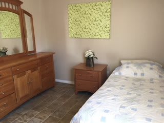 A cozy bedroom with a bed, dresser, and nightstand featuring simple decor.