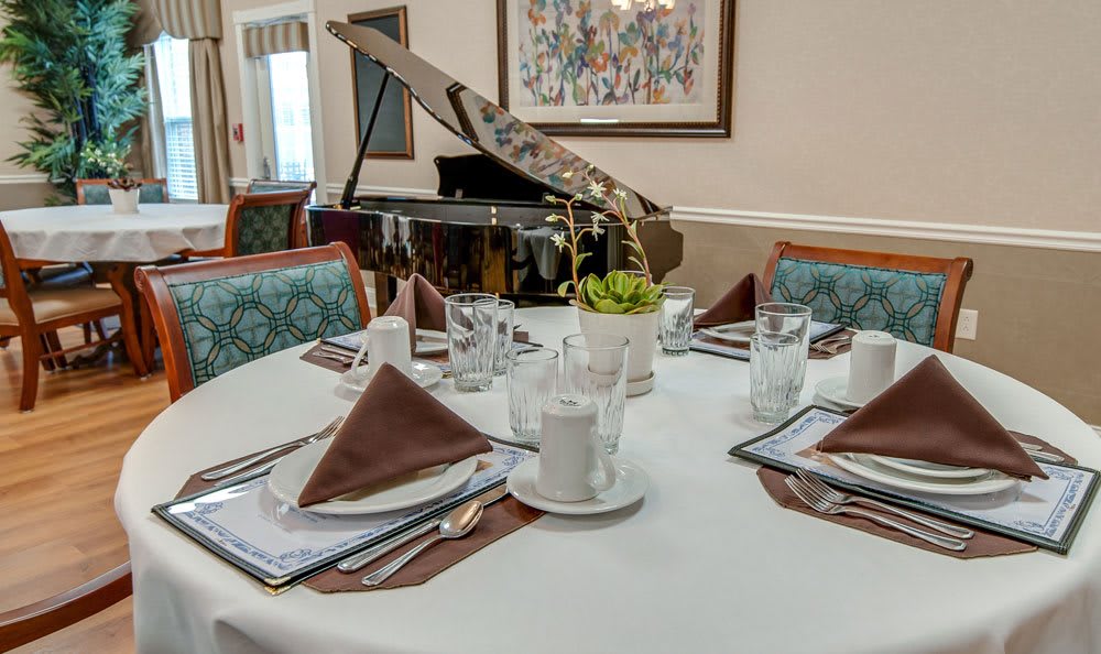 An elegantly set dining table with a piano in the background.