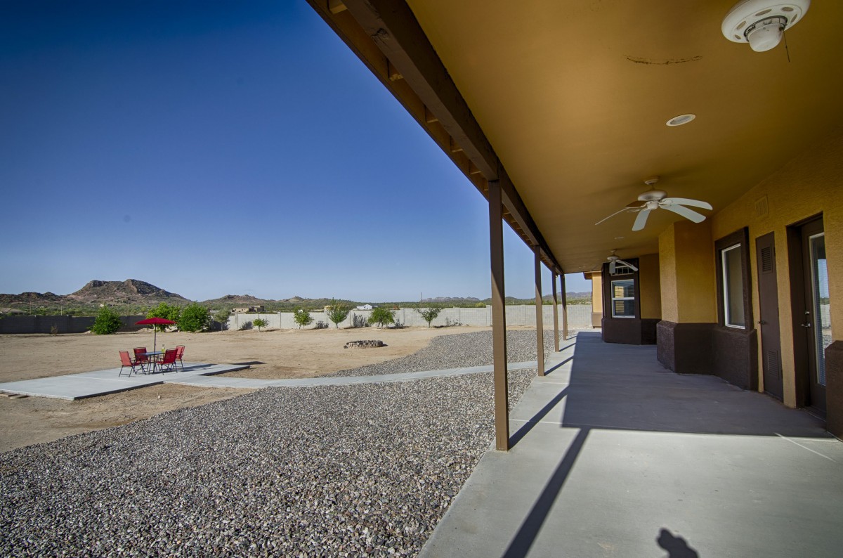 A patio overlooking a desert landscape with clear skies and rocky terrain.