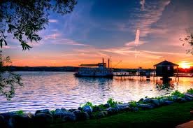 A peaceful lake scene at sunset with a boat near the pier.