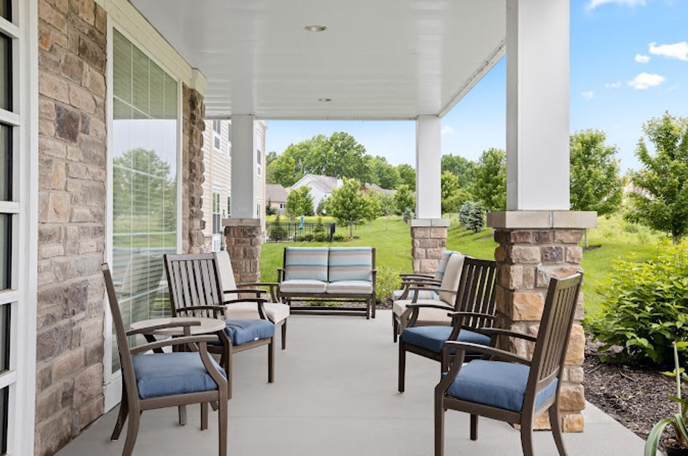 A spacious porch with comfortable seating and a view of a landscaped garden.