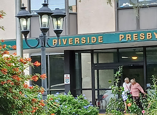 Entrance to Riverside with vibrant flowers and classic street lamps.
