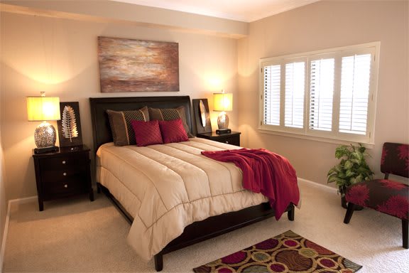 A cozy bedroom interior with a large bed, warm lighting, and decorative elements.