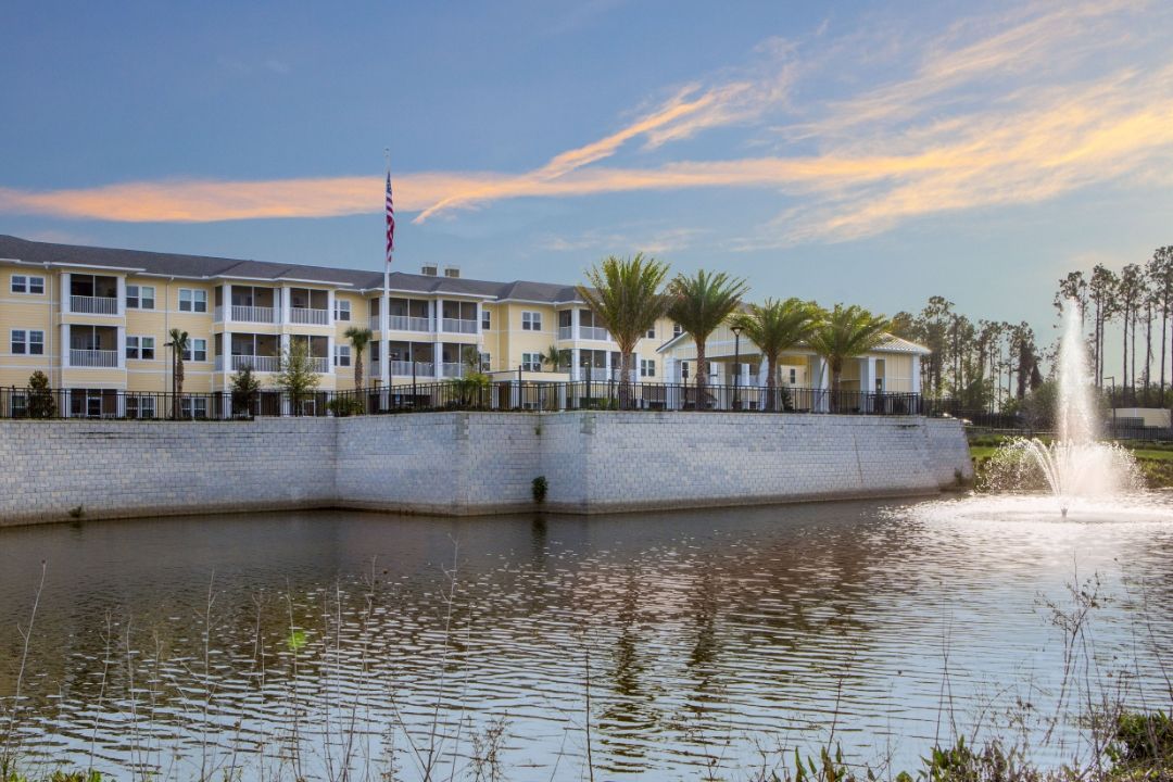 A waterside building with palm trees at sunset.