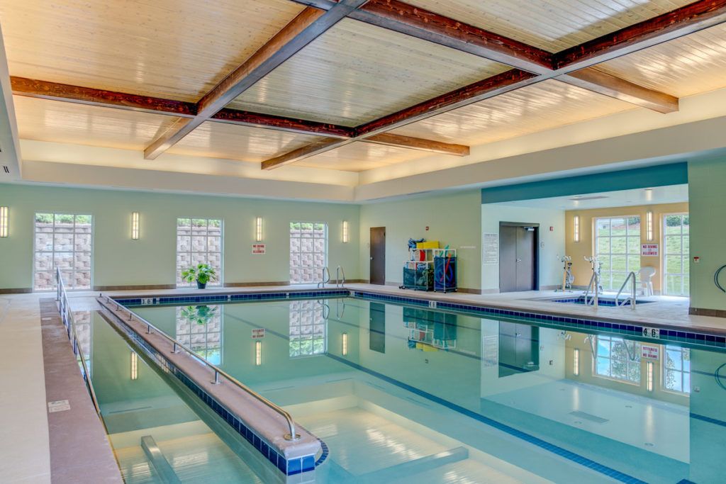 A well-lit indoor swimming pool with modern design and large windows.