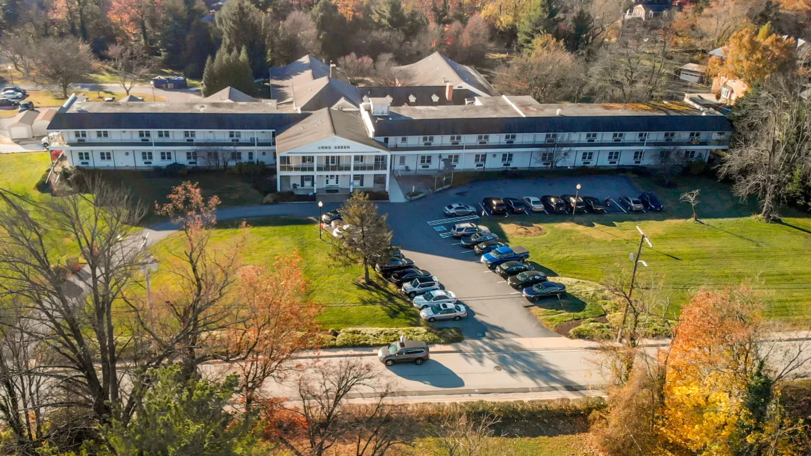 Aerial view of a large building with a parking lot surrounded by autumn foliage.