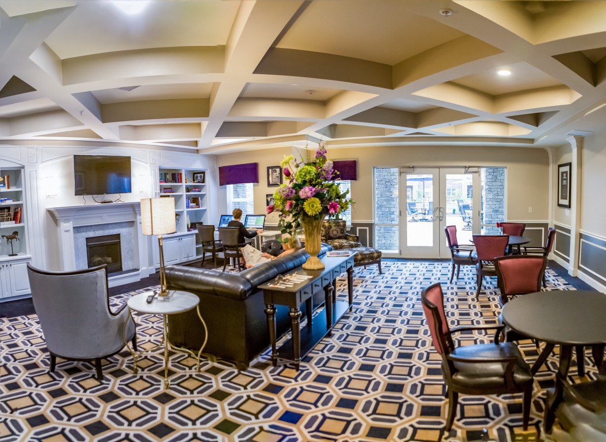 A modern office interior with patterned carpet, elegant furniture, and a large floral arrangement.